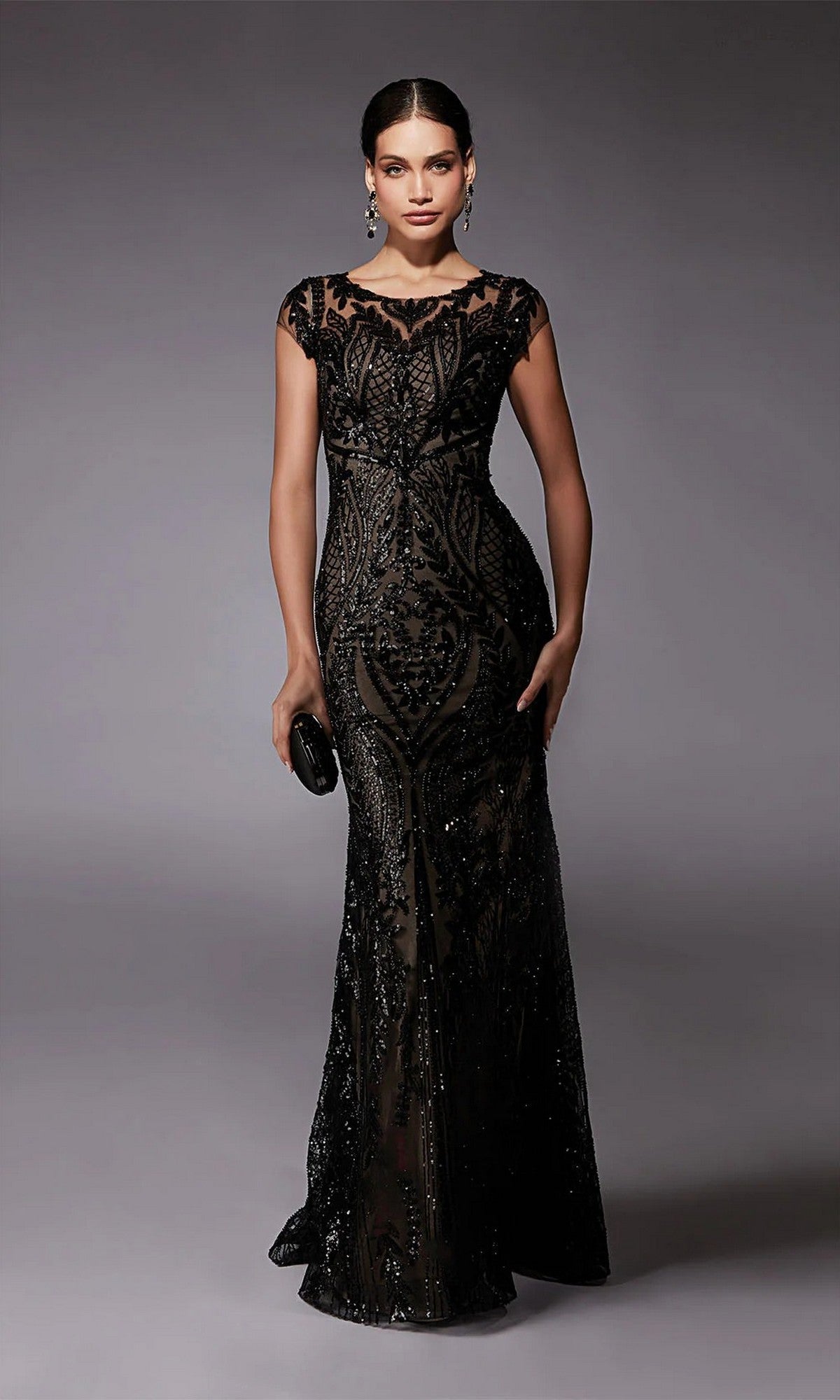 A woman poses against a plain gray background wearing the Alyce 27716 long formal dress in Black/Taupe, paired with a small black clutch.